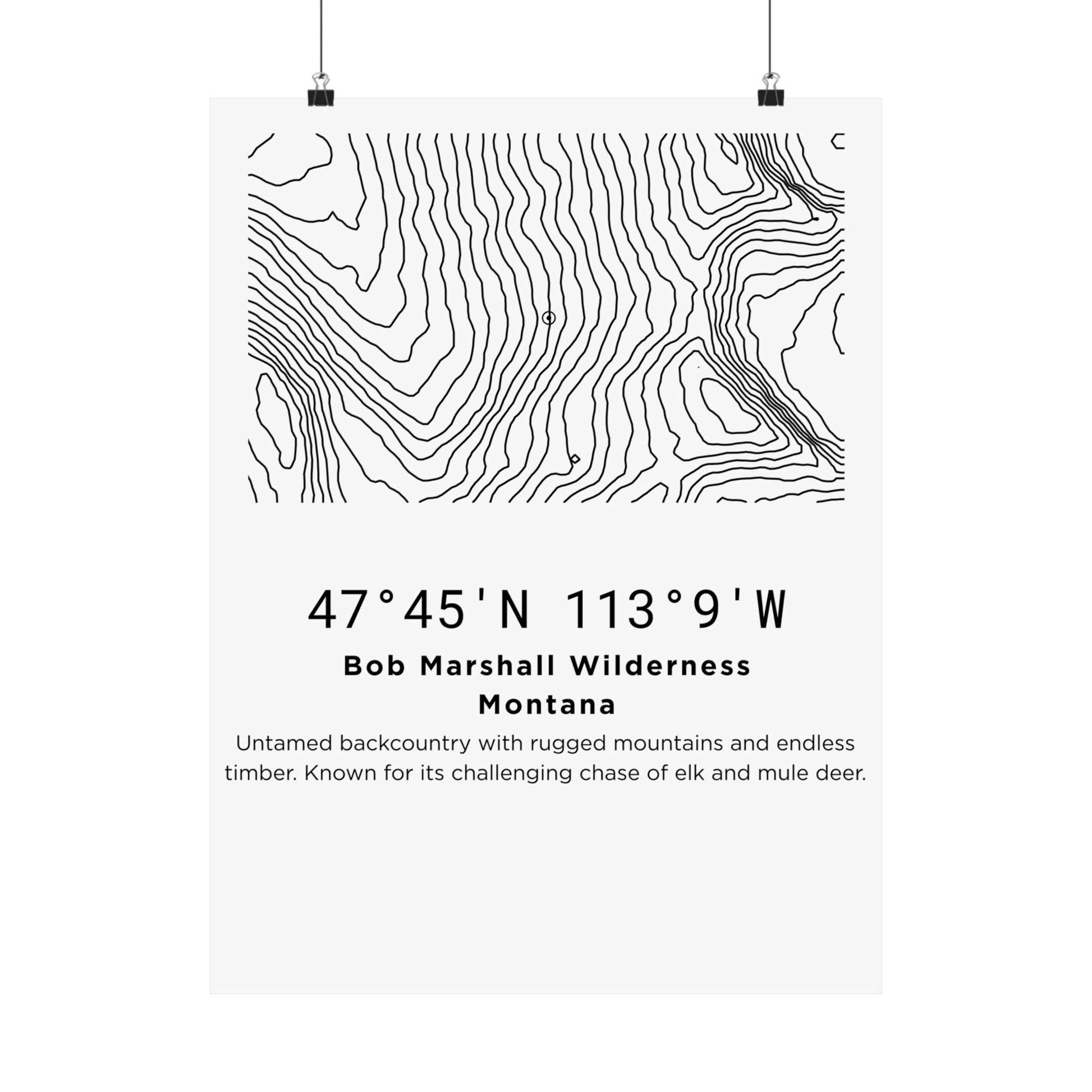 Full flat view of the Bob Marshall Wilderness Montana minimalist topographic map poster hung with binder clips, displaying the contour line art, coordinates, and location description text on off-white matte paper.
