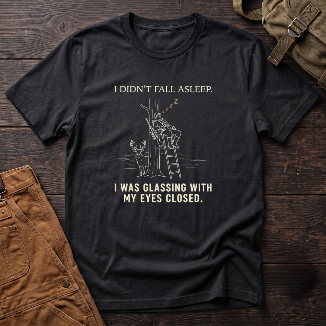 Black funny deer hunting t-shirt with I Didn't Fall Asleep, I Was Glassing With My Eyes Closed text and a line-art hunter dozing in a ladder stand while a whitetail buck stands below