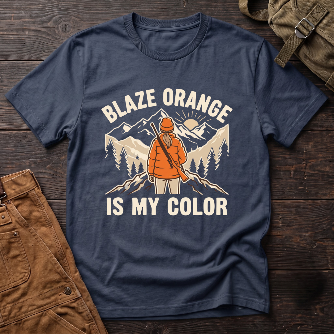 Navy women's hunting t-shirt with Blaze Orange Is My Color lettering and a woman hunter in blaze orange with a rifle facing a mountain sunrise