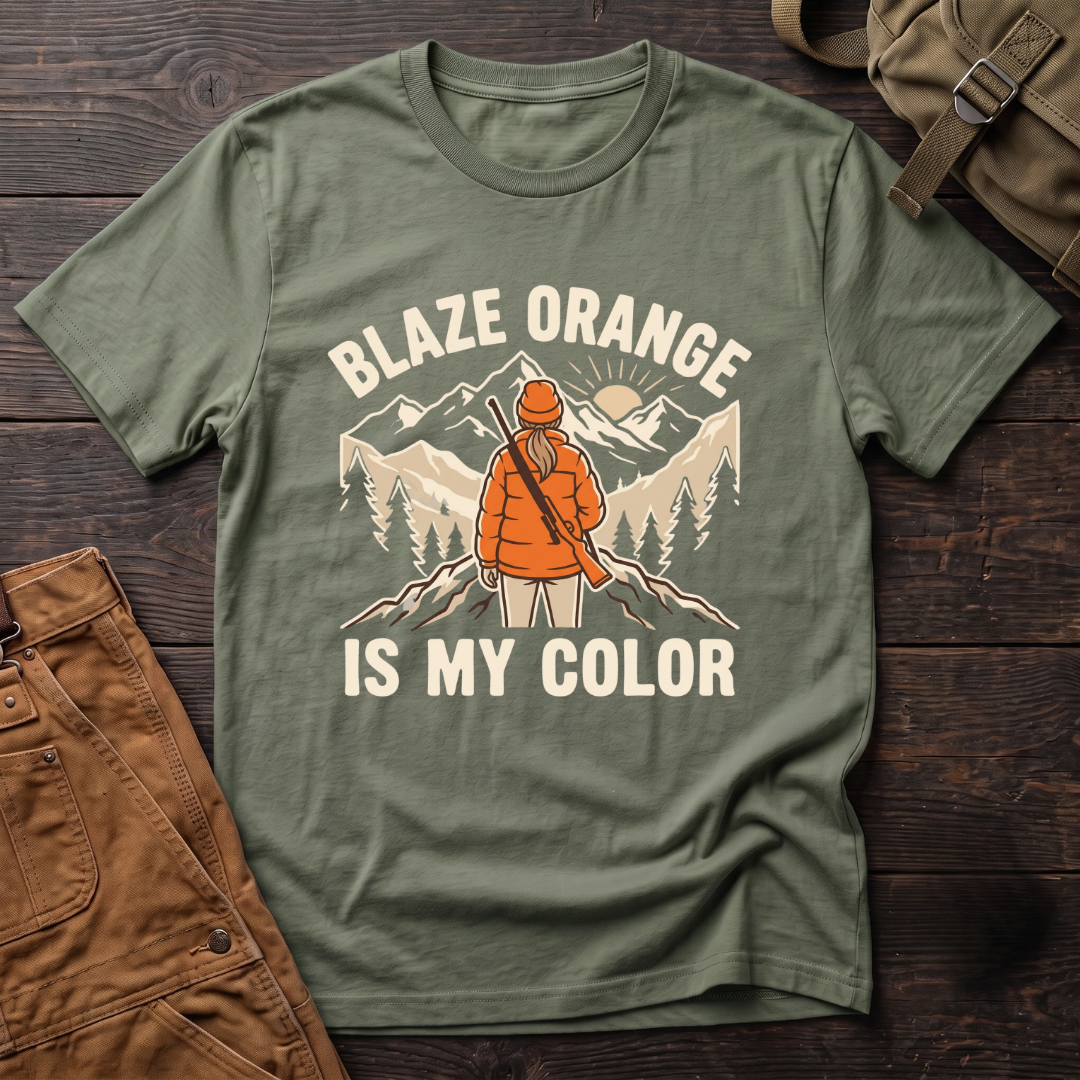 Military Green women's hunting t-shirt with Blaze Orange Is My Color lettering and a woman hunter in blaze orange with a rifle facing a mountain sunrise
