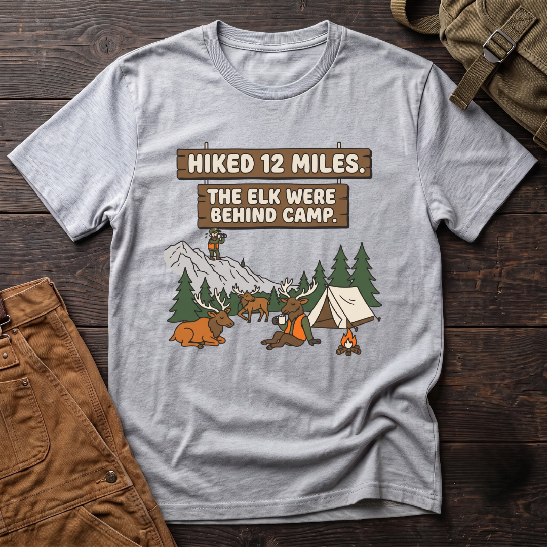 Athletic Heather funny elk hunting t-shirt with Hiked 12 Miles. The Elk Were Behind Camp. signs and elk walking past a tent while the hunter glasses far away