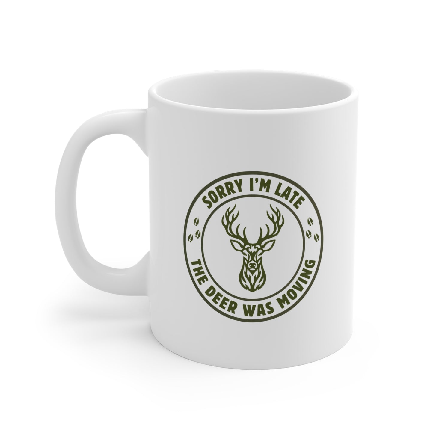 White ceramic hunting mug with a funny Sorry I'm Late the Deer Was Moving slogan and tribal whitetail deer badge graphic in olive green, shown from the left side on a white background.